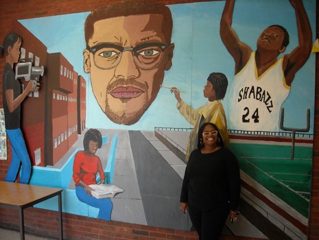 Ms. Crawford poses by a mural at Shabazz High School